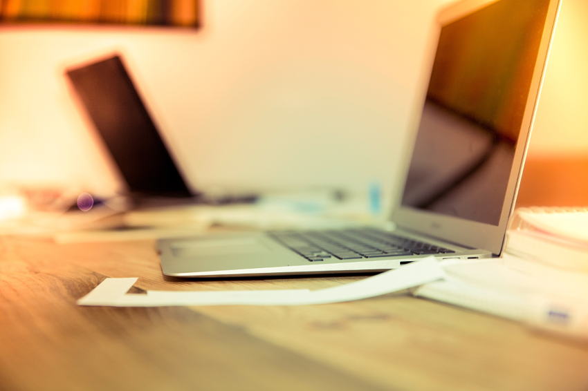 A Laptop sitting on a table along with some papers